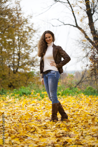 Autumn fashion image of young woman walking in the park