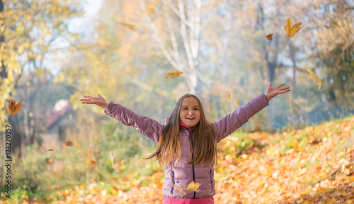 Счастливый подросток девочка в осеннем лесу подбрасывает вверх листья 