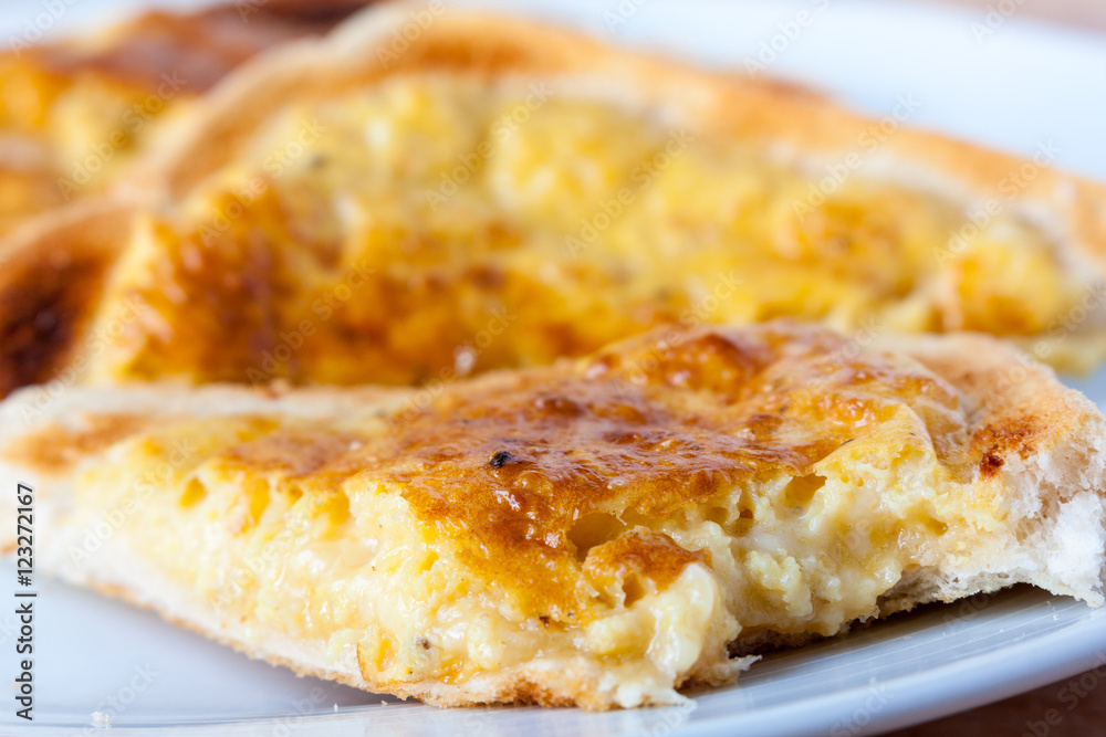 Close-up of a slice of welsh rarebit, a type of cheese on toast, with a bite taken out of it Close-up of a slice of welsh rarebit, a type of cheese on toast, with a bite taken out of it