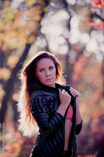 Girl in autumn leaves in a leather jacket