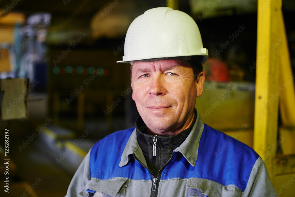 Portrait of a Builder in overalls and helmet in the premises of the plant