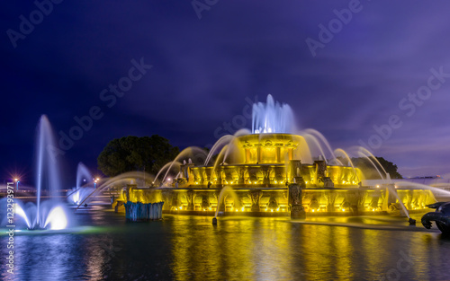 Chicago skyline panorama with skyscrapers and Buckingham fountain in Grant Park at night lit by colorful lights.