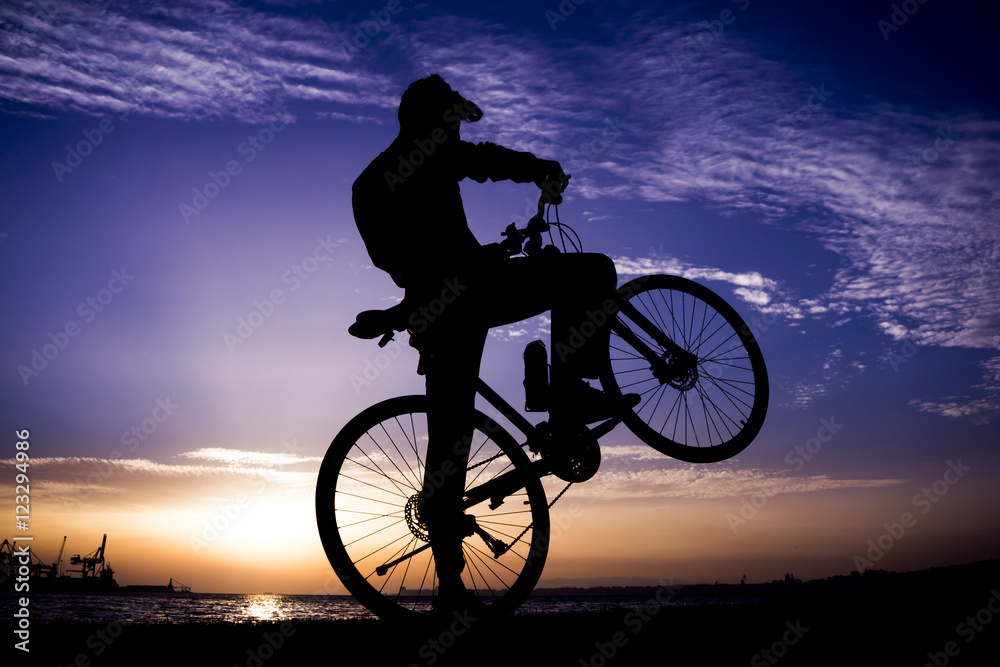 Obraz premium Silhouettes of biking man at beautiful sunset