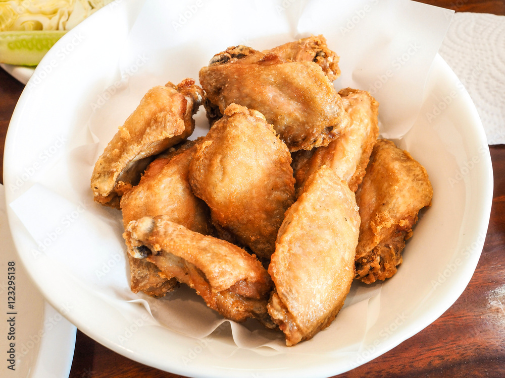 Fried chicken in a white bowl on a wooden table. Fried chicken in a white bowl on a wooden table.
