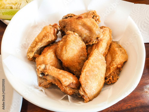 Fried chicken in a white bowl on a wooden table.