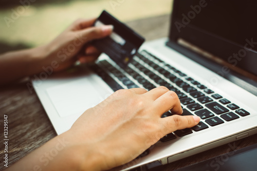 Woman Hands holding credit card and using laptop on wooden table