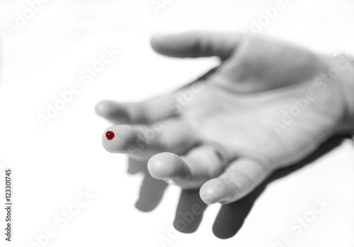 A finger with red blood drop