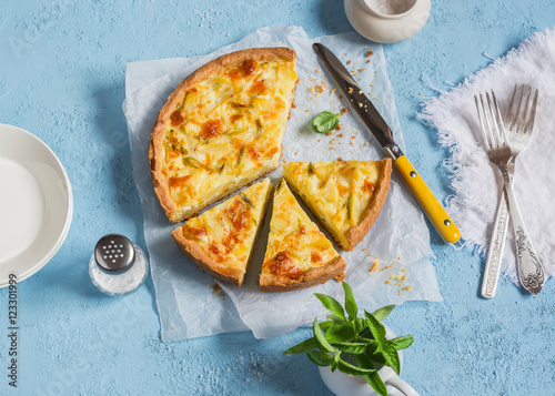 Leek, potato and cheese pie on a blue background, top view.