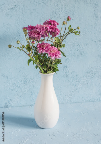 Fototapeta Naklejka Na Ścianę i Meble -  Flowers chrysanthemums in a white vase on a blue background.