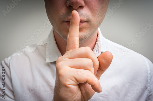 Attractive man with finger on lips making silence gesture photo