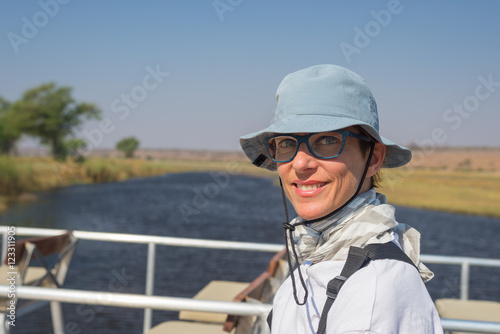 Portrait of smiling woman with green eyes and cheerful facial expression. Natural daylight, natural skin, shot outdoors while sailing on Chobe River, Namibia, Africa. © fabio lamanna