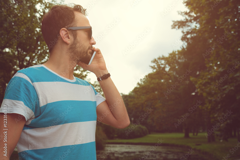 Fototapeta premium Guy talking on his smartphone outdoors.