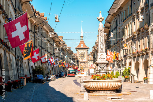 Street view on Kramgasse with fountain and clock tower in the old town of Bern city. It is a popular shopping street and medieval city centre of Bern, Switzerland