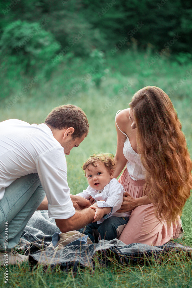 Young beautiful father, mother and little toddler son against green trees Young beautiful father, mother and little toddler son against green trees