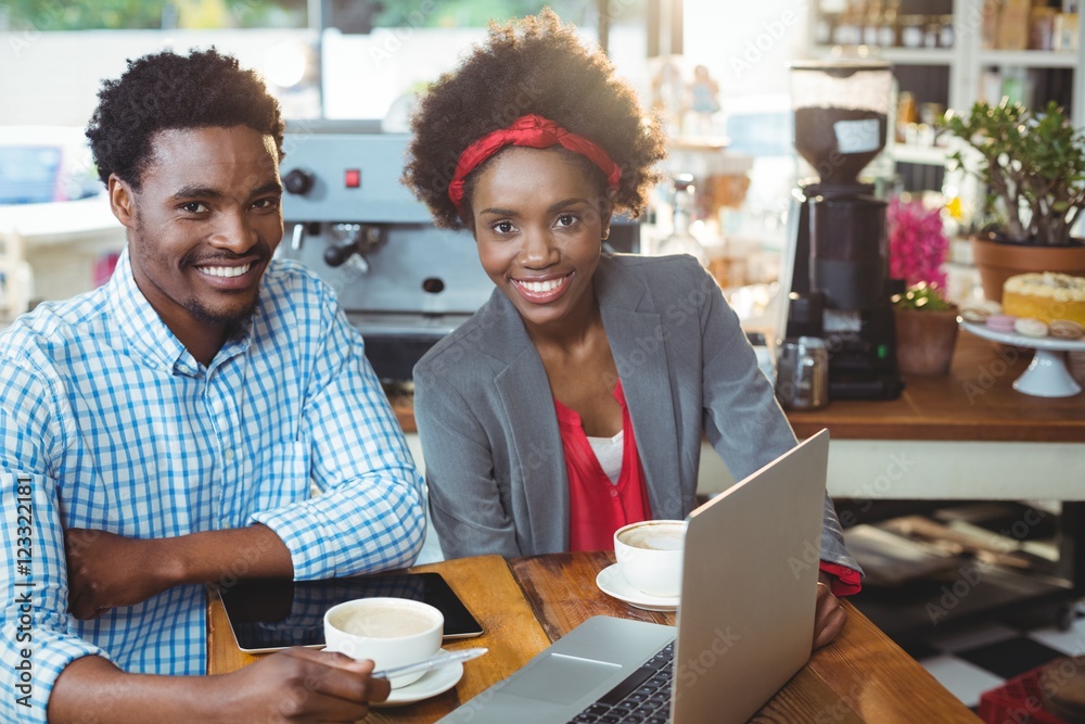 Man and woman using a laptop while having cup of coffee Man and woman using a laptop while having cup of coffee