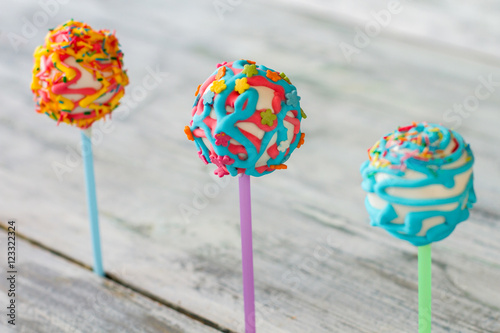 Three candies on sticks. Cake pops on blurred background. How to make day happier. Positive energy and appetite.