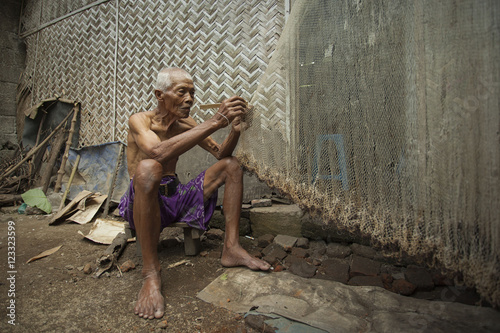 Senior man repairing a fishing net, Jember, East Java, Indonesia