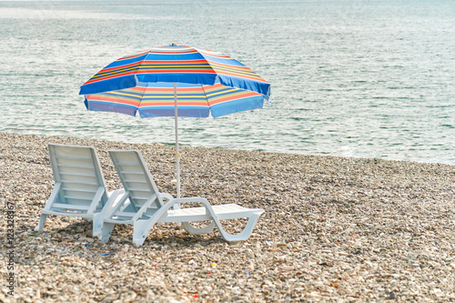 Two empty sunbeds and umbrella on the pebble beach of Batumi, Georgia