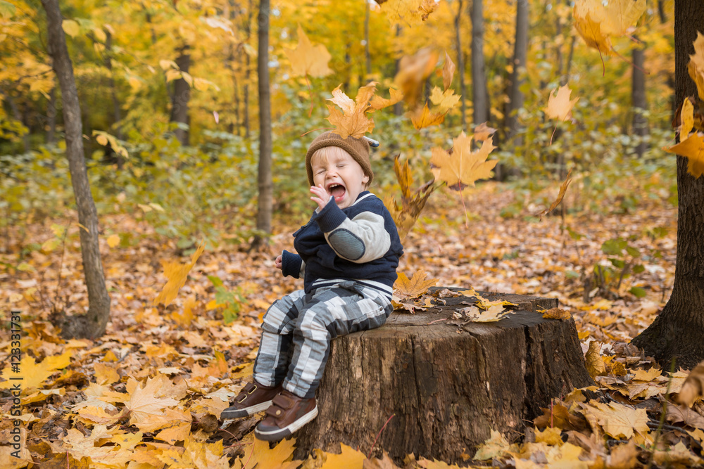 Beautiful baby boy one years old crawling in fallen leaves - autumn scene Beautiful baby boy one years old crawling in fallen leaves - autumn scene