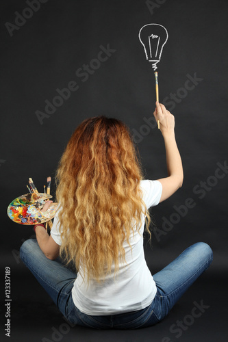 Woman artist draws on a dark background. The concept of idea.