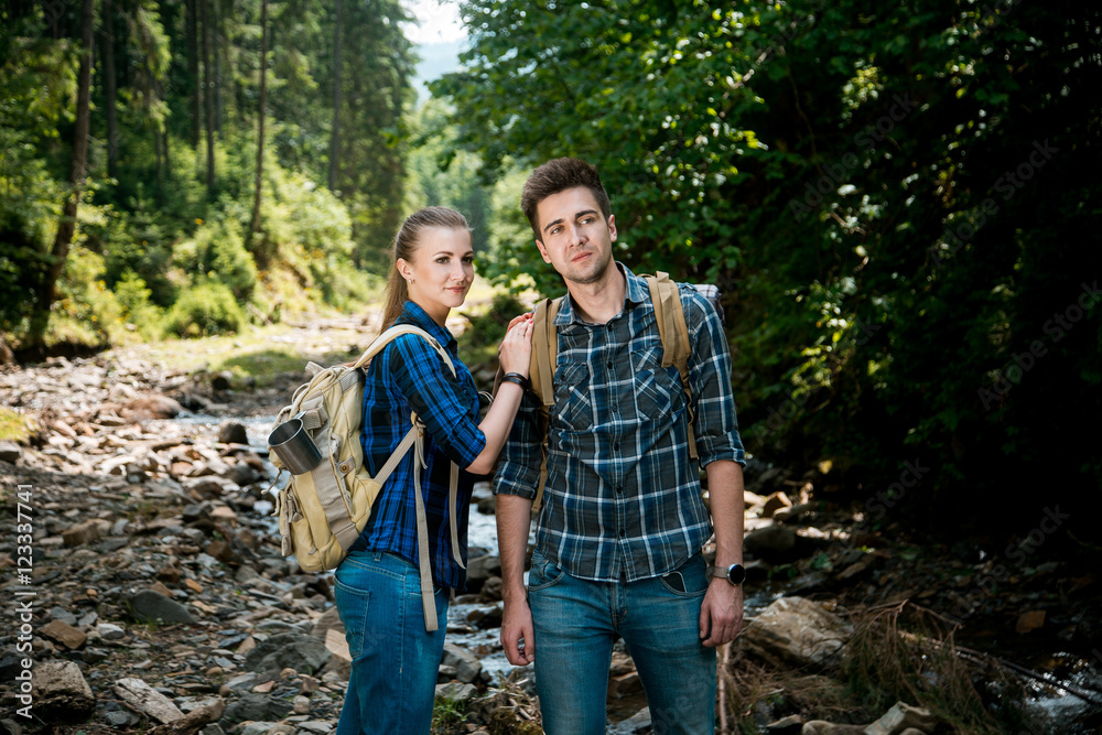 Man and woman tourists walking hand in hand through the woods in the mountains
