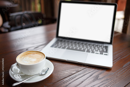 Laptop with white blank screen and cup of latte