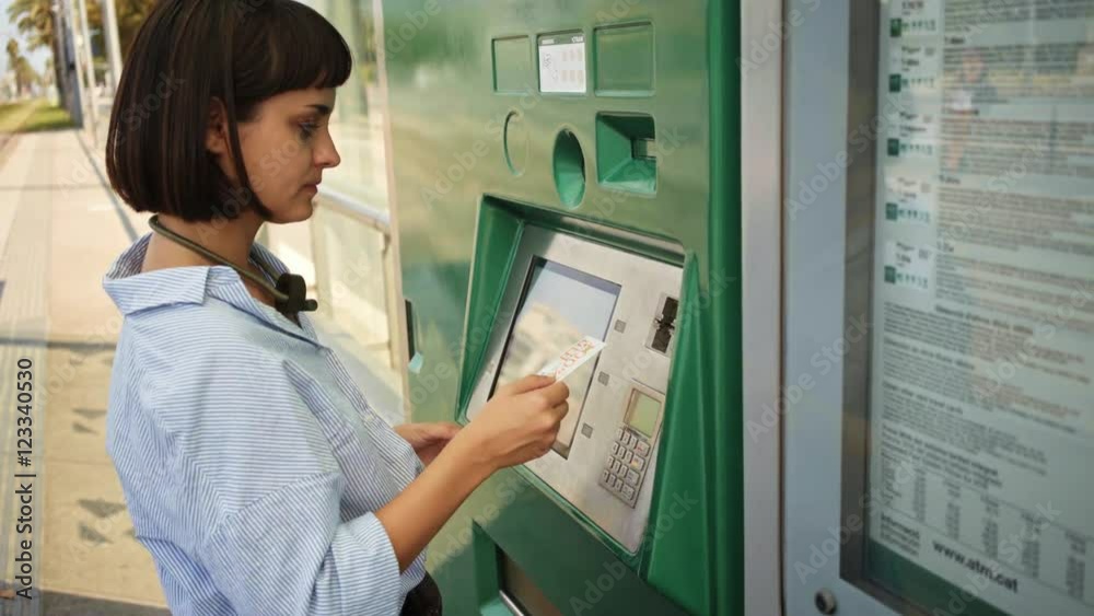 Pretty brunette girl uses vending machine to buy public transport ticket with her credit card Pretty brunette girl uses vending machine to buy public transport ticket with her credit card