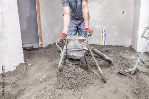 Employee performs sand and cement screed floor.