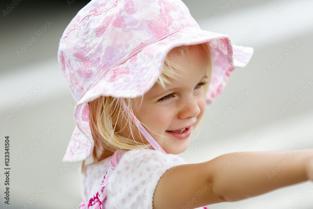 Charming little caucasian girl in pink hat smiling