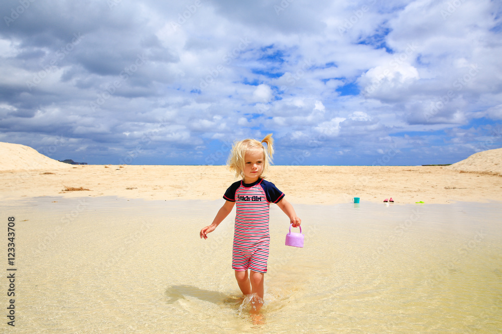 Beautiful blond-haired girl walking on the beach