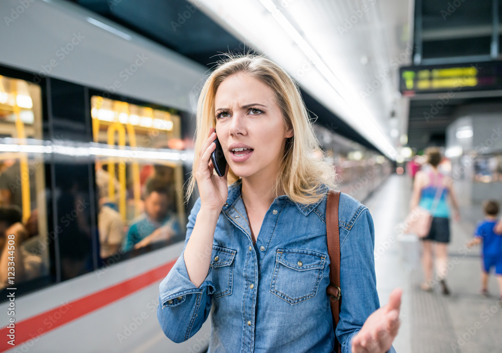 Woman making phone call at the underground platform, waiting