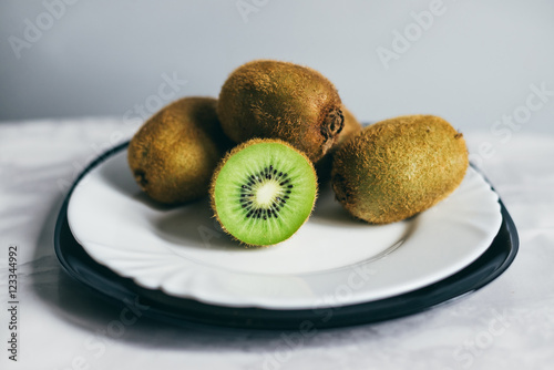 A pile of ripe kiwi on a white plate