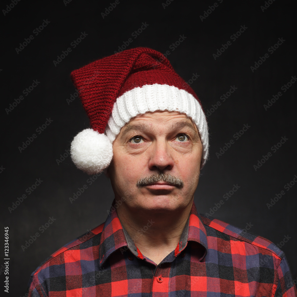 Man in New Year's cap looks sad. Bad mood before Christmas Man in New Year's cap looks sad. Bad mood before Christmas