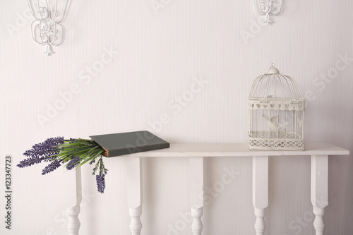 Book with flowers and a bird cage in the room on a shelf photo