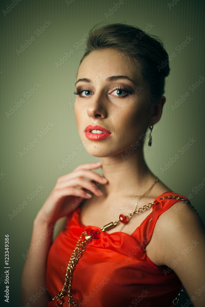 Gorgeous girl holds fingers on the neck while posing in orange d