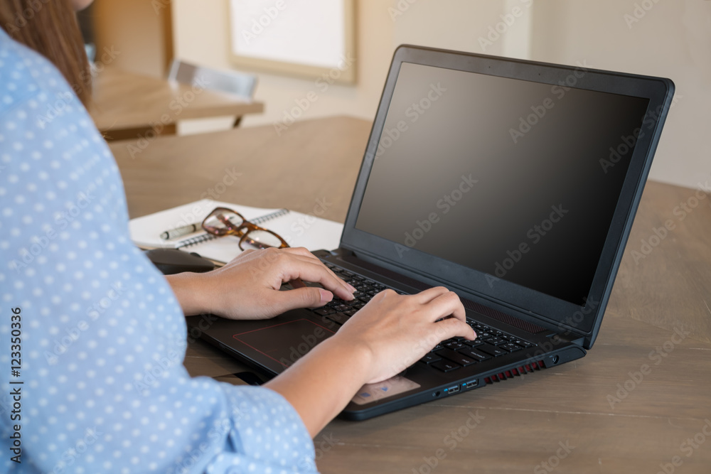 Naklejka premium Preview Save to a lightbox Find Similar Images Share Edit Stock Photo: Woman using laptop on tablet on wooden table in coffee shop with a cup of coffee.