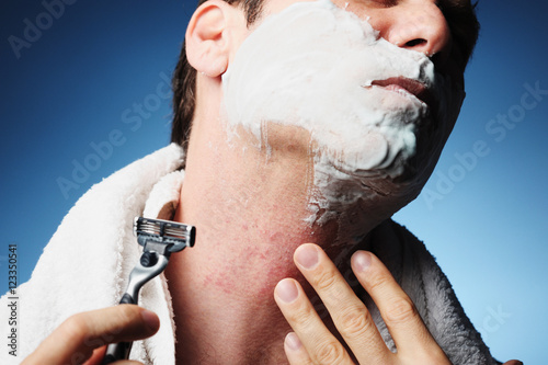 Closeup miserable male man shaving with razor burn bumps nicks cuts rash easily isolated photo