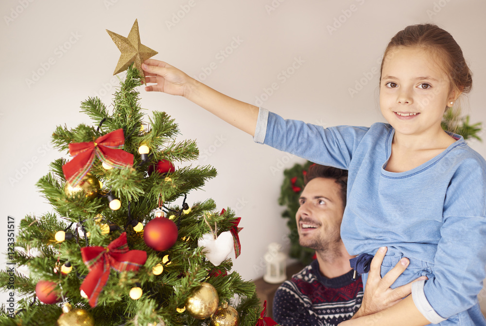 Girl and her daddy decorating the Christmas tree Girl and her daddy decorating the Christmas tree