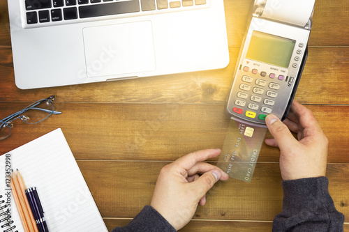 Cashier hand holding a Credit card over EDC machine or credit card terminal with calculator and glasses. A credit card over japanese bank notes.
