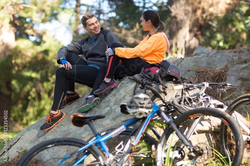 Biker couple interacting with each other in forest