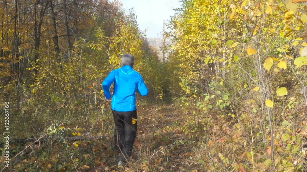Man jogging cross country running on trail in forest. Training and exercising outdoors when cross country running in inspirational autumn landscape. Sports Motivation. Slow Motion. Man jogging cross country running on trail in forest. Training and exercising outdoors when cross country running in inspirational autumn landscape. Sports Motivation. Slow Motion.