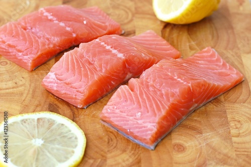 Raw salmon fillet with yellow lemon on brown wooden background
