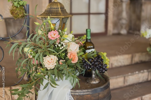 grapes on vase near flowers and bottle of vine