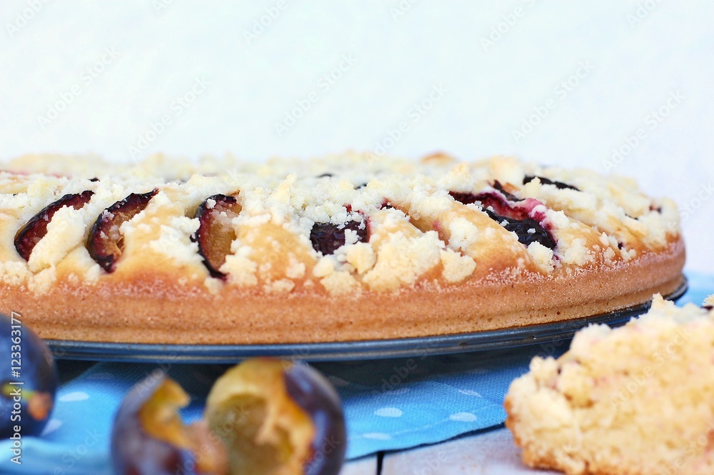 Piece of summer cake with plums on blue cloth on wooden background Piece of summer cake with plums on blue cloth on wooden background