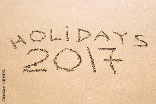 Happy Holidays 2017. Written in sand at the beach. Holiday, Christmas, New Year 2017 concept.