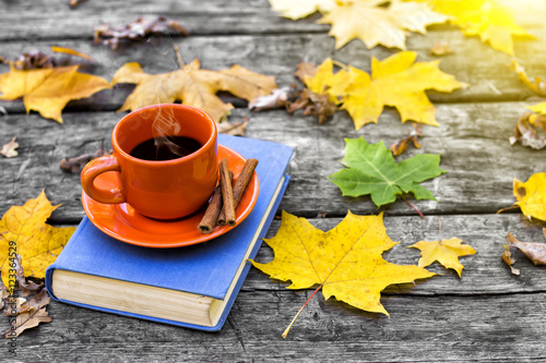 The book and cup of hot coffee on the old wooden table, covered in yellow maple leaves. Back to school. Education concept. Beautiful autumn background. Picturesque composition. Weekend in the Park. © igorbukhlin