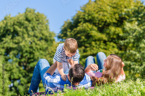 Fototapeta Naklejka Na Ścianę i Meble -  Familie spielt mit Kind im Gras auf der Wiese