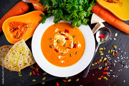 Schilderij op canvas Smooth butternut squash and carrot soup with cream, pumpkin seeds goji berries