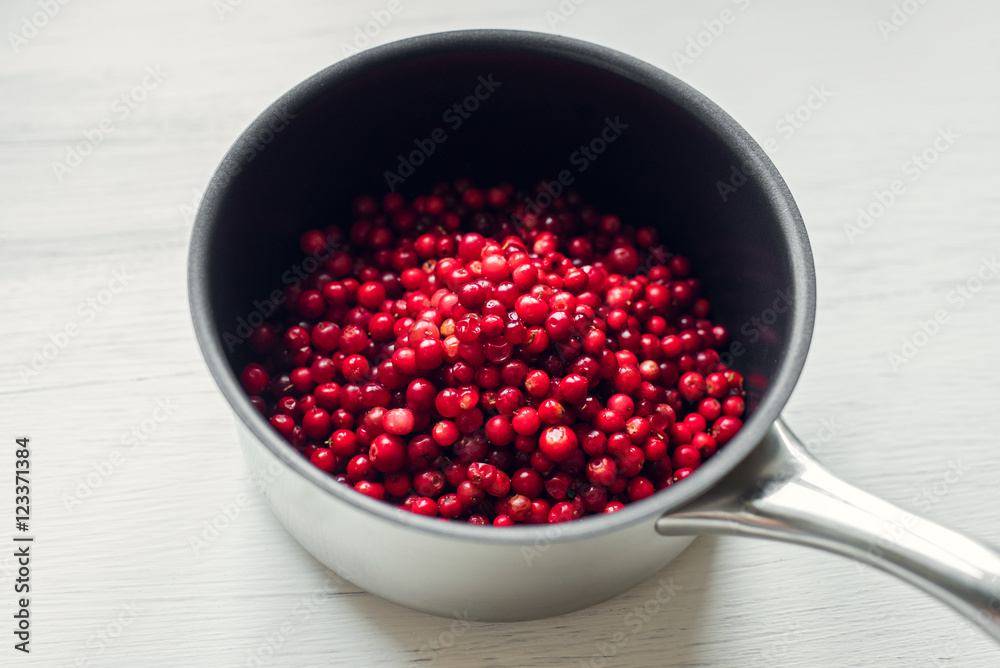 Fresh cranberries in a saucepan on a white wooden table Fresh cranberries in a saucepan on a white wooden table