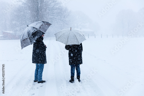 Fototapeta Naklejka Na Ścianę i Meble -  Paar geht im Schneeschauer spazieren